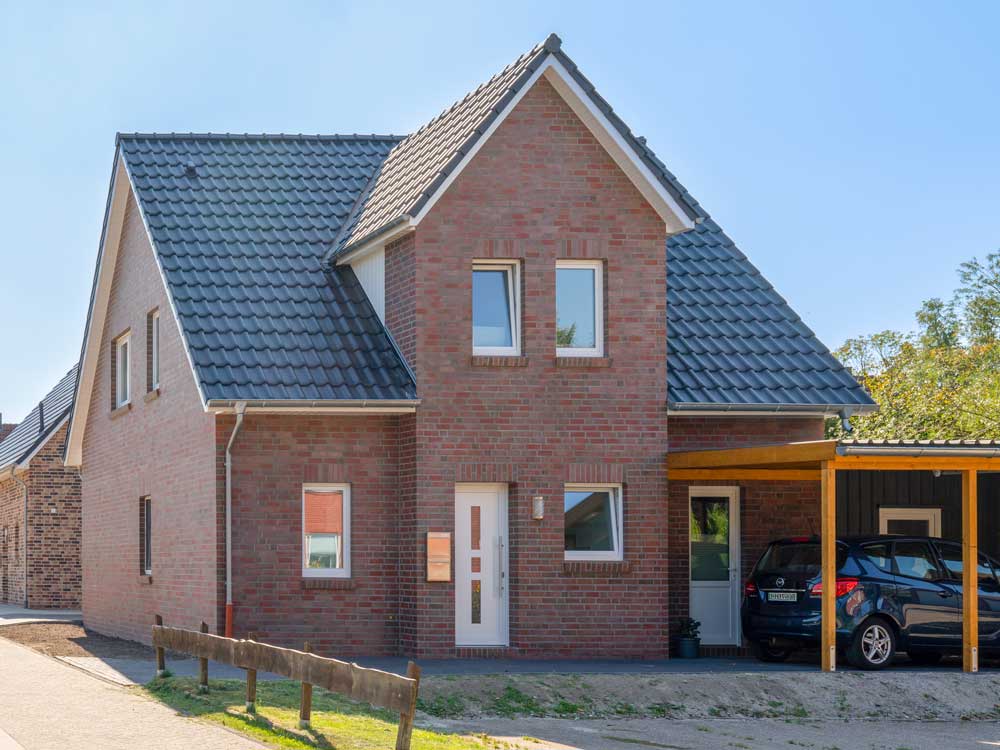 Zweistöckiges Backsteinhaus mit Satteldach und angebautem Carport